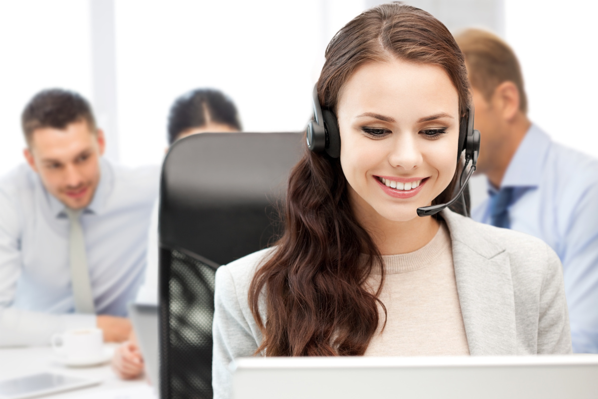 A smiling person with a headset and other people in the background