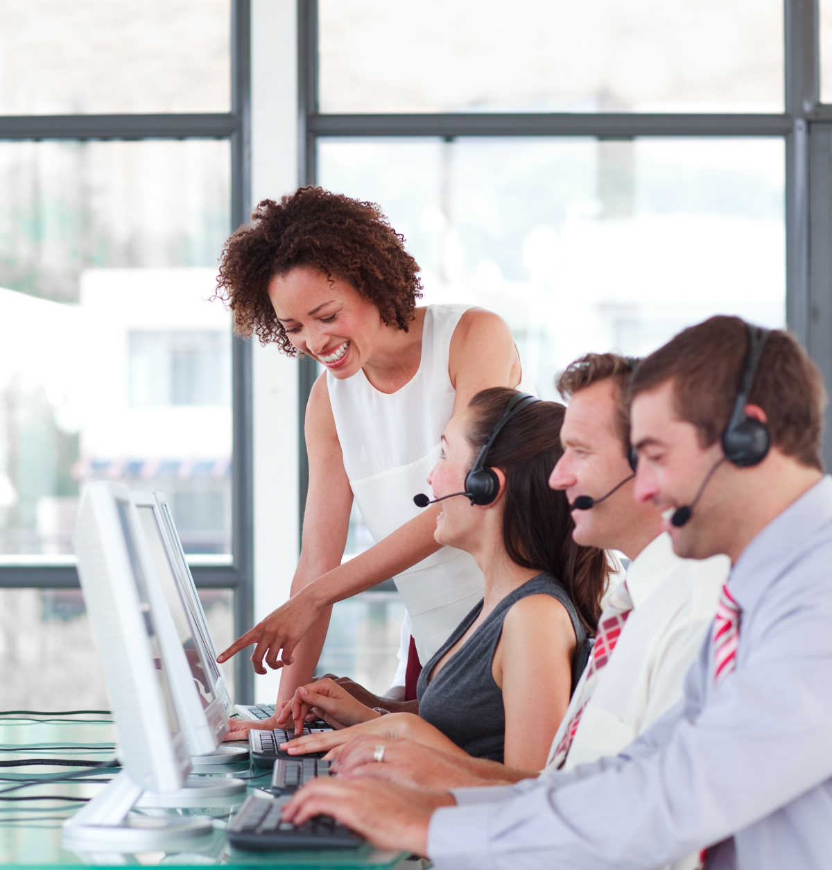 Help desk employees with headsets sitting at their computers