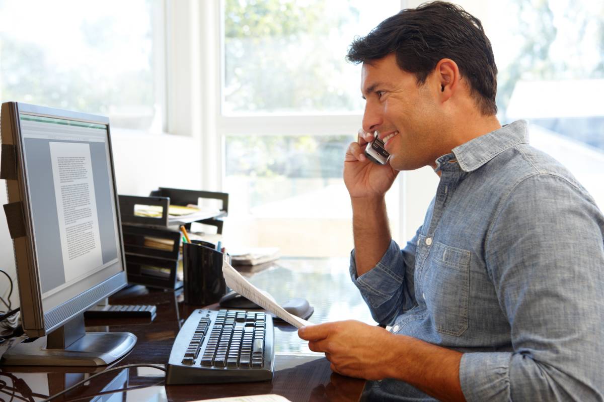 A man in a blue button up shirt working from home in his office