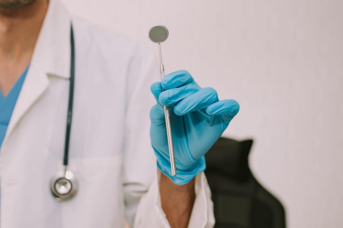 Dentist holding a dental mirror in a treatment room.